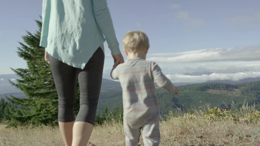 Woman and baby walk through dry grass
