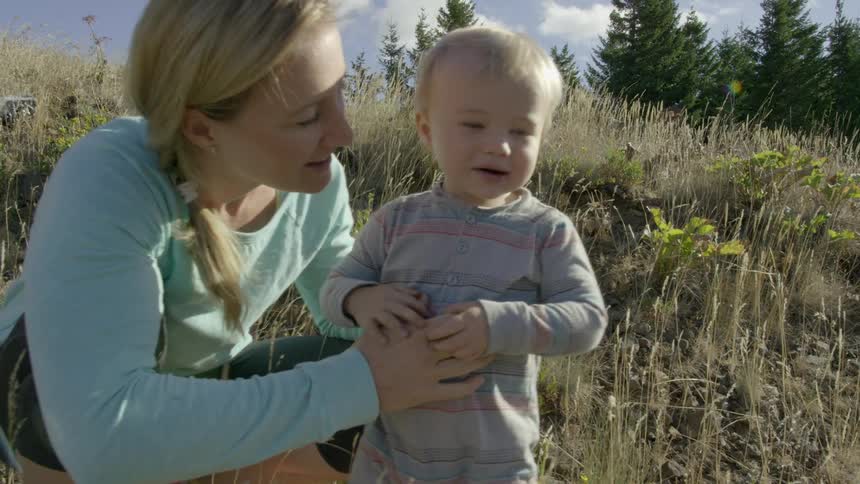 A woman and a baby in a field with clouds in the background
