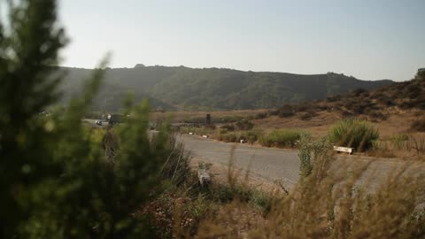 A busy rural road in the distance with lots of cars going by during the day