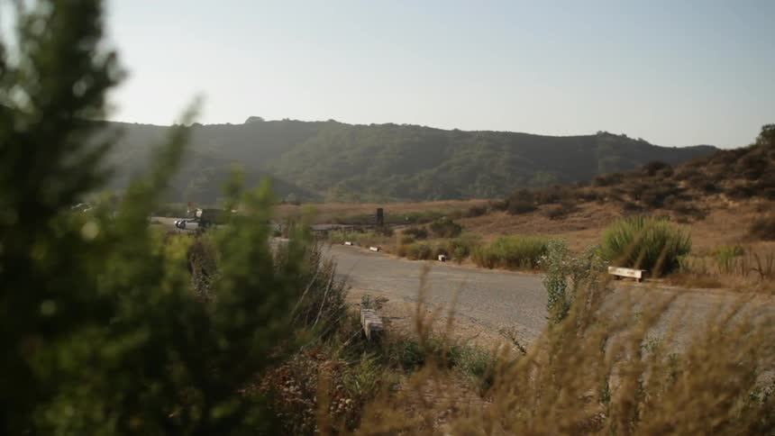 A busy rural road in the distance with lots of cars going by during the day