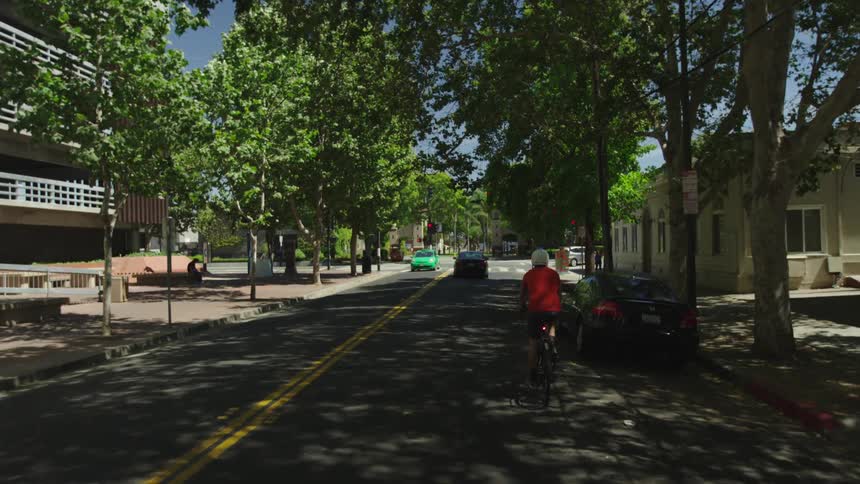 A person rides a bike down a shady street