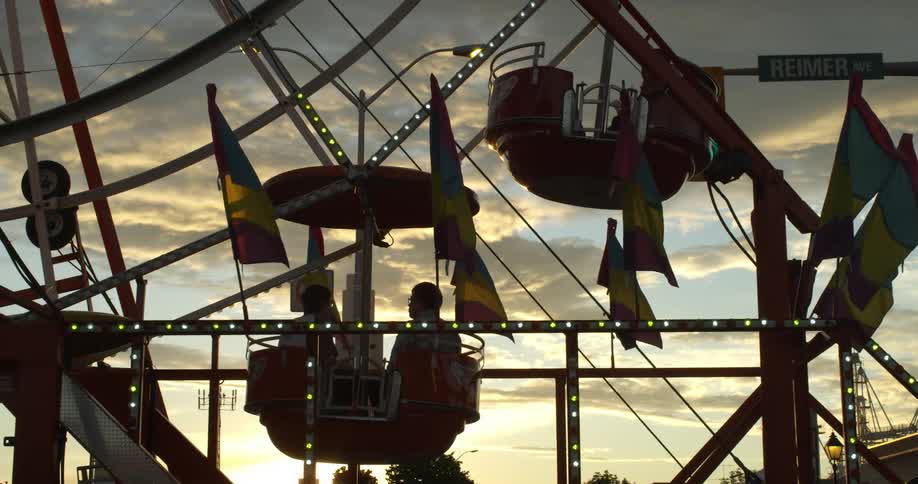 People riding ferris wheel at sunset
