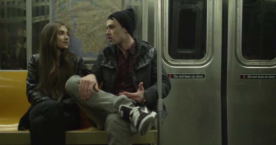 A man and woman chat as they ride the subway