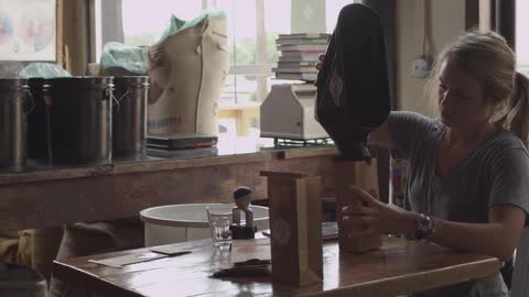 Woman pours coffee into a brown bag