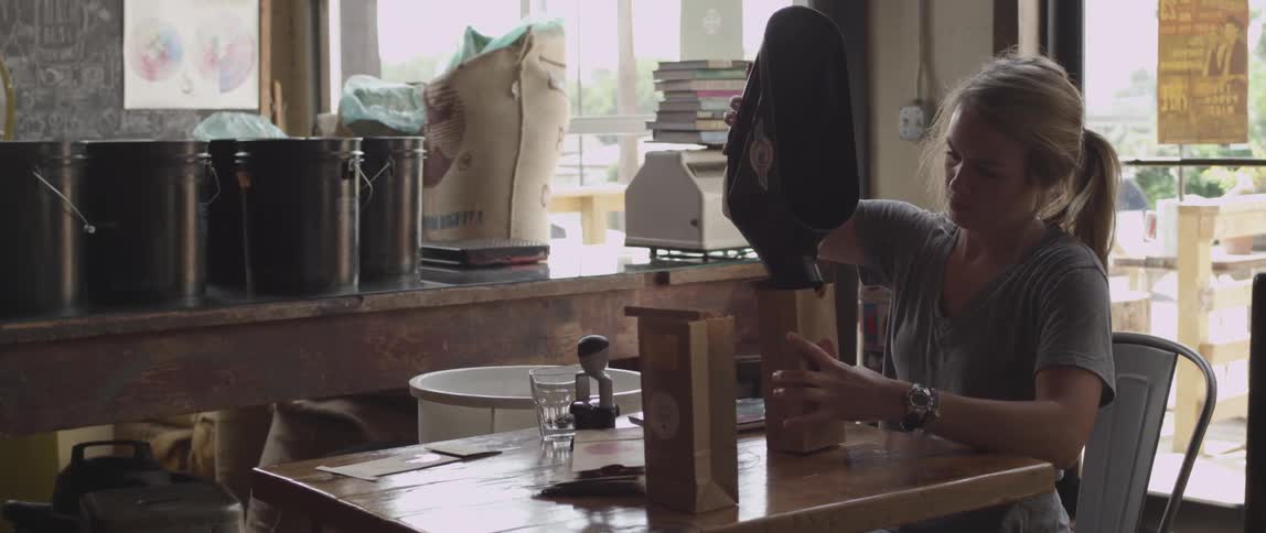 Woman pours coffee into a brown bag