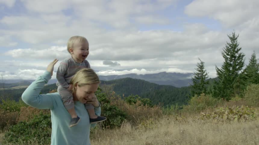 A mother walks with her toddler on her shoulders