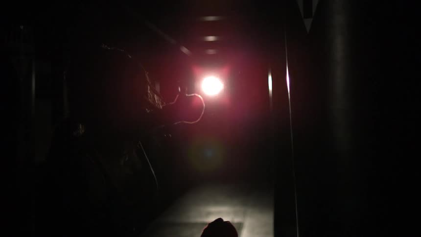 A person punches a punching bag in a dark room
