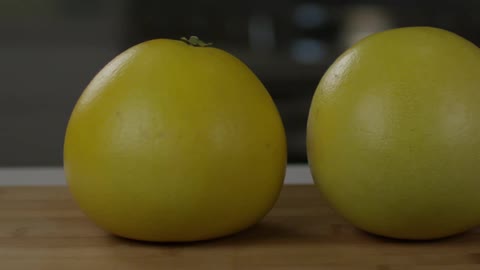 Two lemons sitting on a cutting board