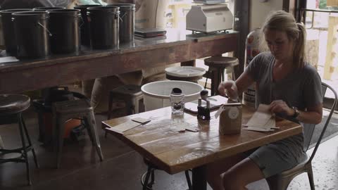 A woman sits at a table and stamps paper bags