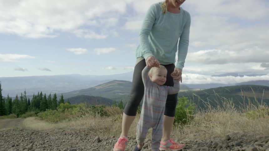 A mother and her baby hike up a rugged trail deep in the woods while they explore the landscape