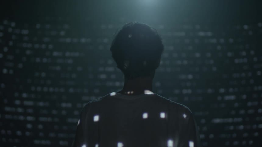 Projected lights in dashes and dots flash over the back of a person and all around him
