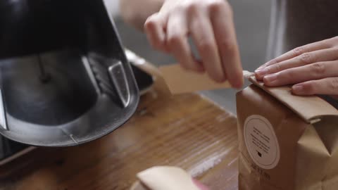 A woman ties a tag around a brown paper bag