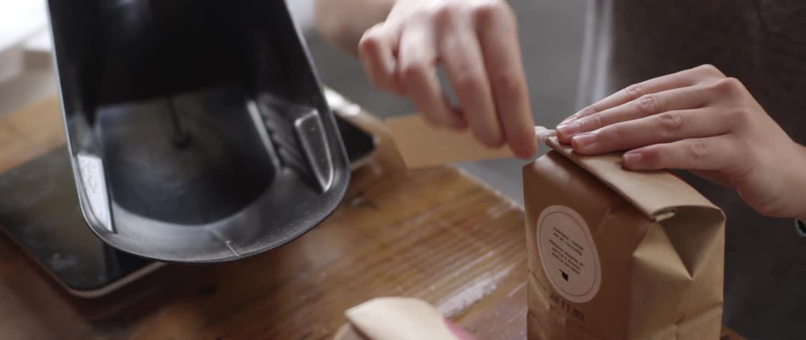 A woman ties a tag around a brown paper bag